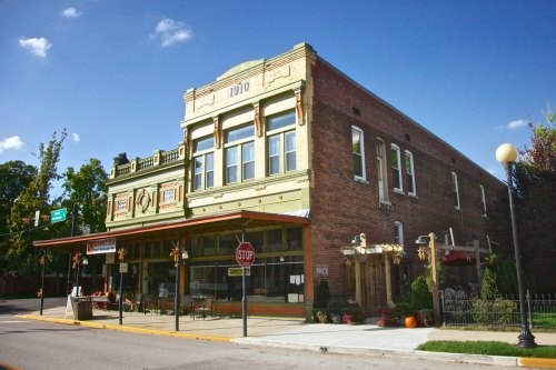 Historic brick building with decorative facade, featuring large windows and a porch, set against a clear blue sky.