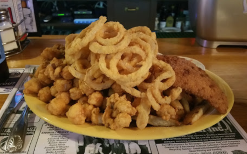 A large plate of fried seafood, including calamari and onion rings, served with a side of fries.