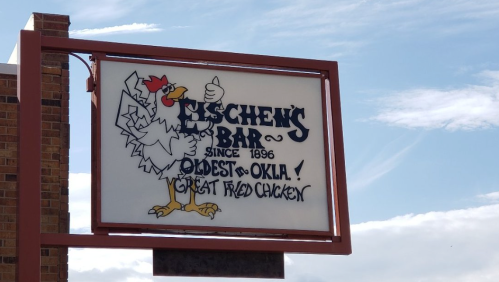 Sign for Kischel's Bar, established in 1896, featuring a cartoon chicken and text about great fried chicken.