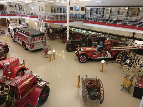 A museum display featuring vintage fire trucks and equipment in a spacious, well-lit gallery.