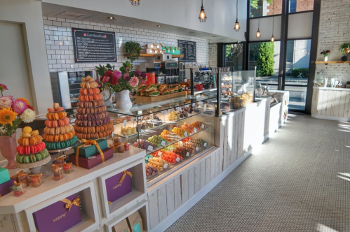 A bright bakery display featuring colorful pastries, macarons, and a variety of desserts in a cozy, inviting setting.