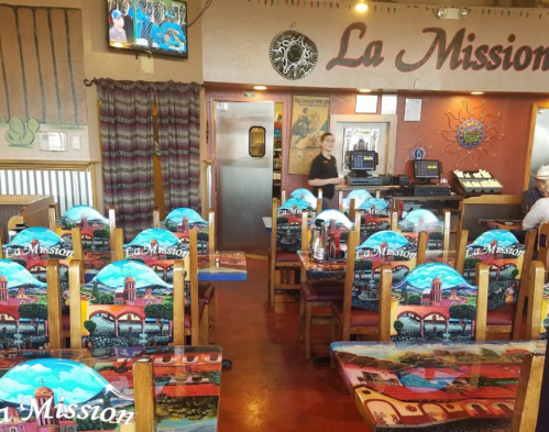 Interior of La Mission restaurant featuring colorful chairs, a TV, and a warm, inviting atmosphere.
