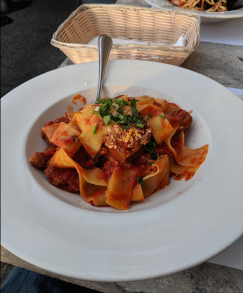 A plate of pappardelle pasta topped with meatballs and marinara sauce, garnished with parsley.