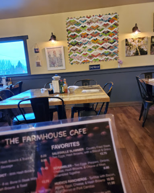 Cozy café interior with wooden tables, a colorful quilt on the wall, and a menu in the foreground.