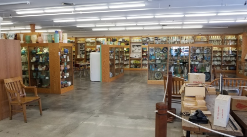 A spacious antique shop with glass display cases filled with various collectibles and vintage items.