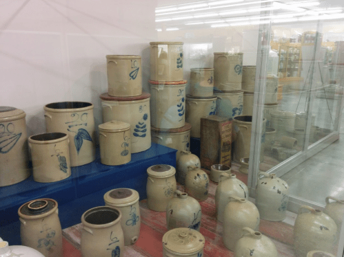 A display of various ceramic jars and containers with blue floral designs in a museum setting.