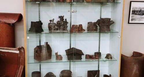 Display case featuring various ceramic and clay sculptures in different shapes and sizes.
