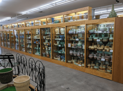A display case filled with various colorful pottery pieces in a museum or gallery setting.