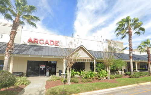Exterior view of an arcade building with palm trees and a blue sky in the background.