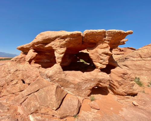 A unique rock formation with arches and a clear blue sky in the background.