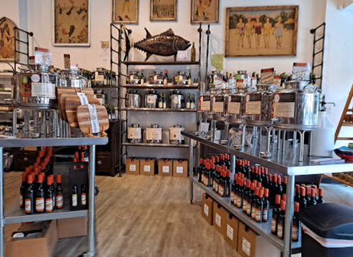 A cozy store interior featuring shelves of bottles, oil dispensers, and decorative artwork on the walls.