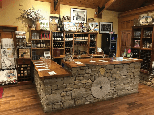 A rustic wine tasting room with a stone counter, wooden shelves filled with bottles, and a cozy, inviting atmosphere.