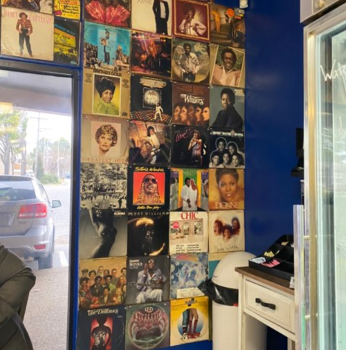 A wall covered with vintage vinyl records and album covers in a cozy, music-themed space.