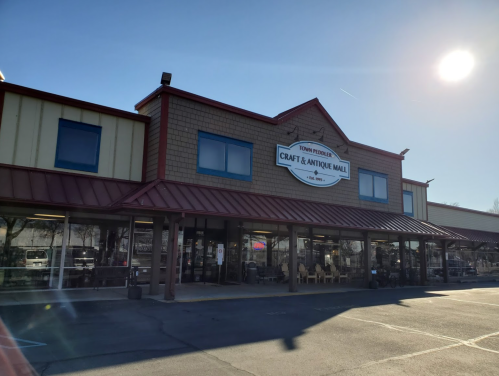 Exterior of Town Pride Craft & Antique Mall, featuring a sign and large windows, under a clear blue sky.