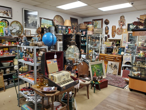 A cluttered antique shop filled with various vintage items, including furniture, decor, and collectibles.