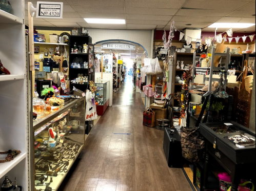 A wide aisle in a vintage shop filled with various antiques and collectibles on display.