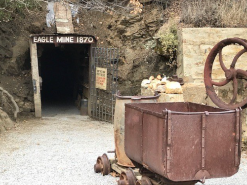 Entrance to Eagle Mine, established in 1870, featuring a gated tunnel and an old mining cart on tracks.