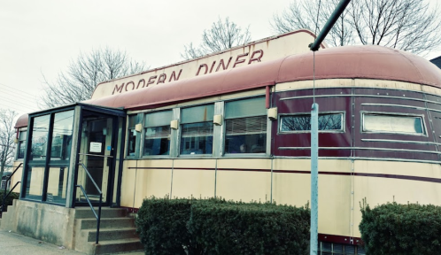 A vintage-style diner with a red and silver exterior, featuring large windows and a welcoming entrance.