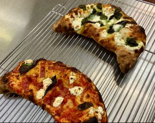 Two freshly baked pizzas on a cooling rack: one with tomato sauce and cheese, the other with broccoli and ricotta.
