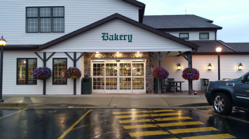 A charming bakery entrance with flower baskets, large glass doors, and a sign reading "Bakery" above.
