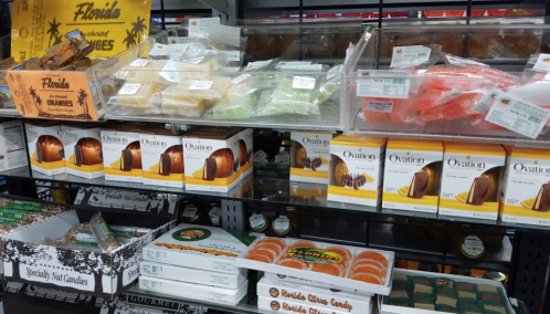 A display of various candies and snacks, including citrus candies and packaged cakes, on a store shelf.