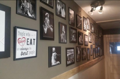 A wall adorned with black-and-white framed photos of musicians, featuring a sign that reads, "People who love to eat are always the best people."