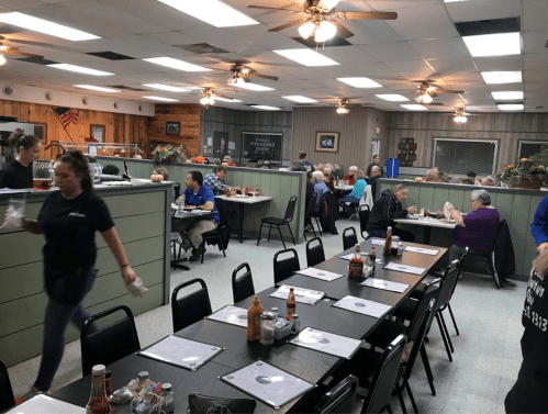 A busy diner with tables filled with customers, waitstaff serving, and a casual, welcoming atmosphere.