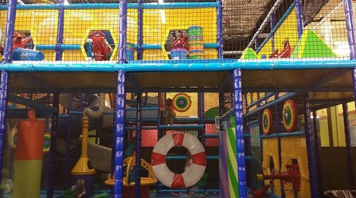 Colorful indoor play structure with nets, slides, and various climbing features for children.