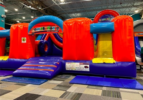 A colorful inflatable bounce house with slides and tunnels, set up indoors on a carpeted floor.
