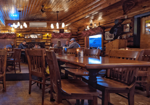 Cozy restaurant interior with wooden decor, tables, and patrons enjoying their meals in a warm atmosphere.