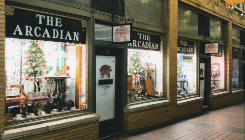 A row of shop windows displaying festive decorations and various items for sale in a brick arcade.