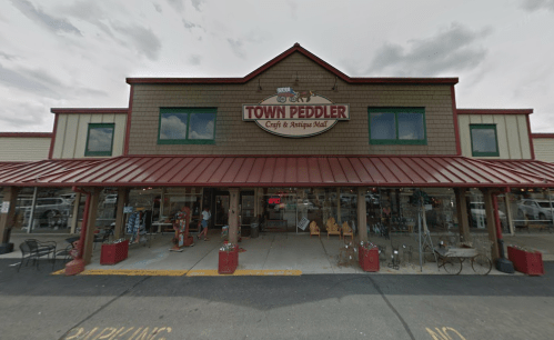 Exterior of the Town Peddler Craft & Antique Mall, featuring a red metal roof and large display windows.