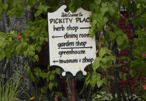 Signpost at Pickity Place with directions to herb shop, dining room, garden shop, greenhouse, and museum & shop.