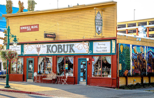 A colorful storefront of The Kobuk, featuring a mural and outdoor seating, in Anchorage, Alaska.