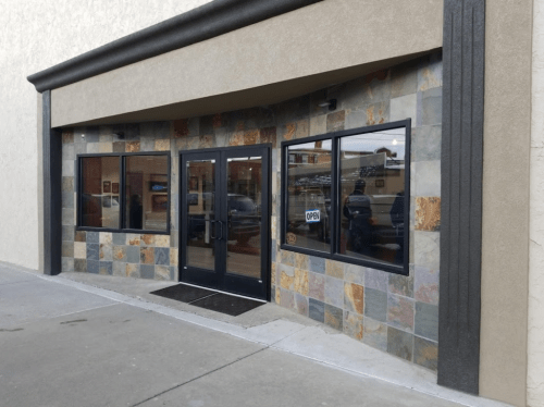 Exterior view of a storefront with a stone facade and large windows, featuring an "Open" sign.