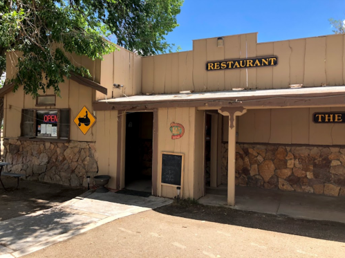A rustic restaurant exterior with a stone facade, open sign, and a chalkboard menu outside.