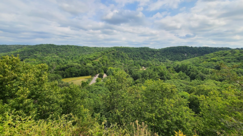 Lush green hills and valleys under a partly cloudy sky, showcasing a serene natural landscape.