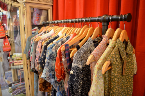 A rack of colorful vintage-style dresses hanging against a red backdrop.