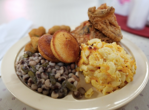 A plate of fried chicken, cornbread, macaroni and cheese, black-eyed peas, green beans, and fried okra.