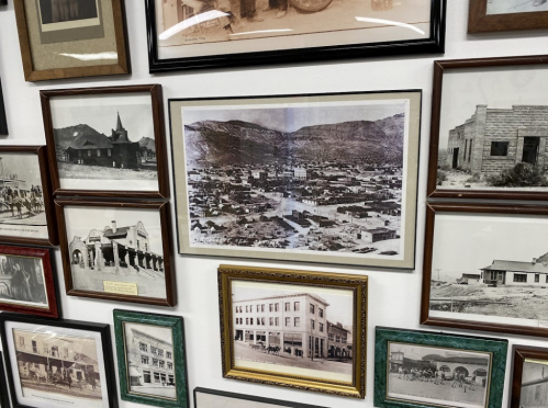 A collage of historical photographs and framed images on a wall, showcasing a town and its buildings.