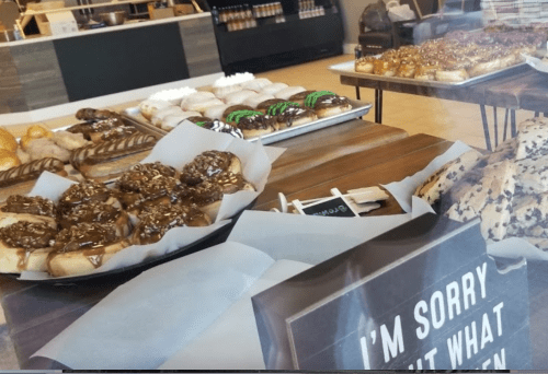 A display of various pastries, including donuts and cinnamon rolls, with a sign that says "I’m sorry about what happened."