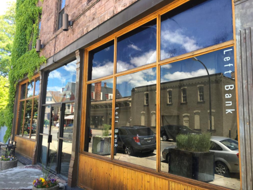 Exterior of a building with large windows reflecting the street, featuring the words "Left Bank" on the glass.
