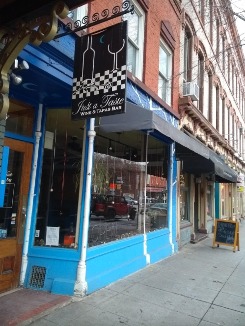 Exterior of a wine and tapas bar with a blue facade, large windows, and a sign that reads "Just a Taste."