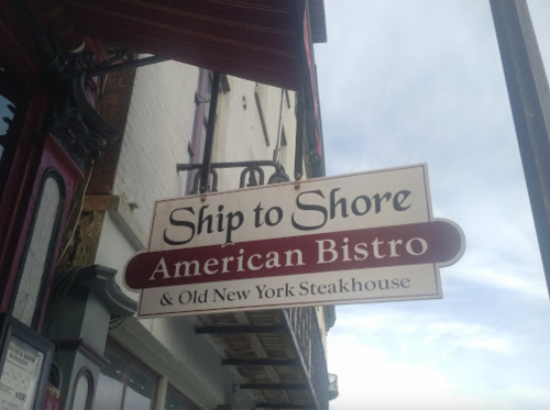 Sign for "Ship to Shore American Bistro & Old New York Steakhouse" hanging outside a restaurant.
