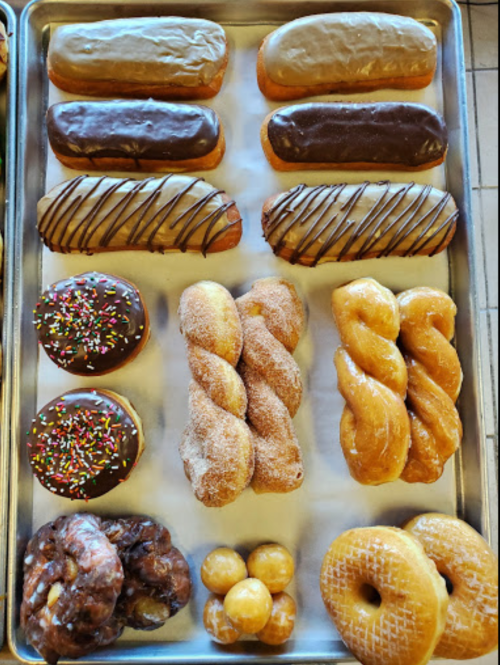 A tray of assorted donuts, including glazed, chocolate, and sprinkled varieties, arranged neatly.