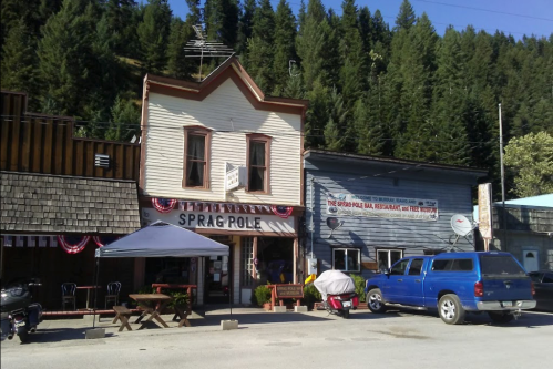Historic building with "Sprag Pole" sign, surrounded by trees and parked vehicles, in a small town setting.