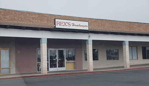 Exterior of Rex's Hamburgers, a casual dining restaurant, with a sign and large windows in a shopping plaza.