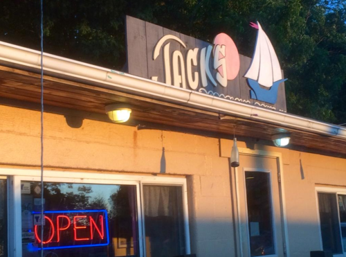 Sign for "Jack's" with a sailboat logo, featuring an illuminated "OPEN" sign in the window.