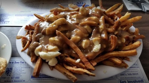A plate of poutine featuring crispy fries topped with cheese curds and rich brown gravy.