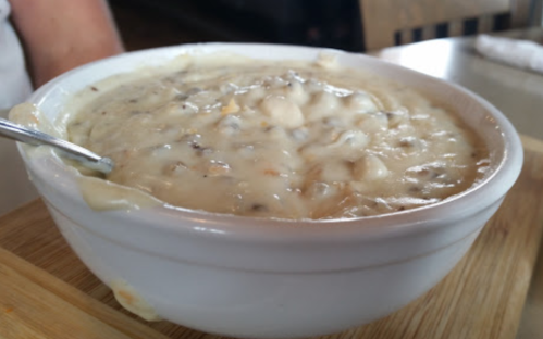 A bowl of creamy soup with a thick texture, served on a wooden surface.